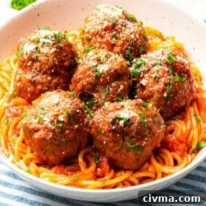 Italian meatballs with parmesan cheese on top of spaghetti.