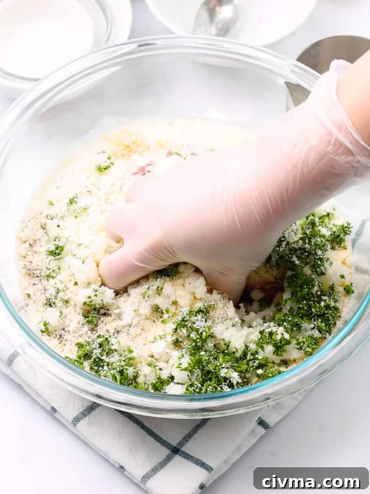 Mixing meatball mixture with hands.
