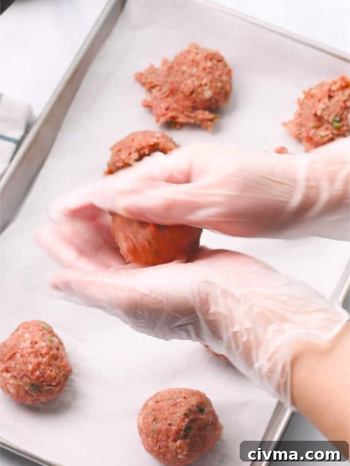 Rolling and shaping meatballs with hands.