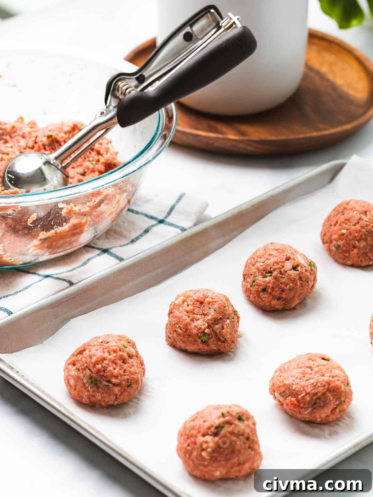 Uncooked meatballs formed on a baking tray.