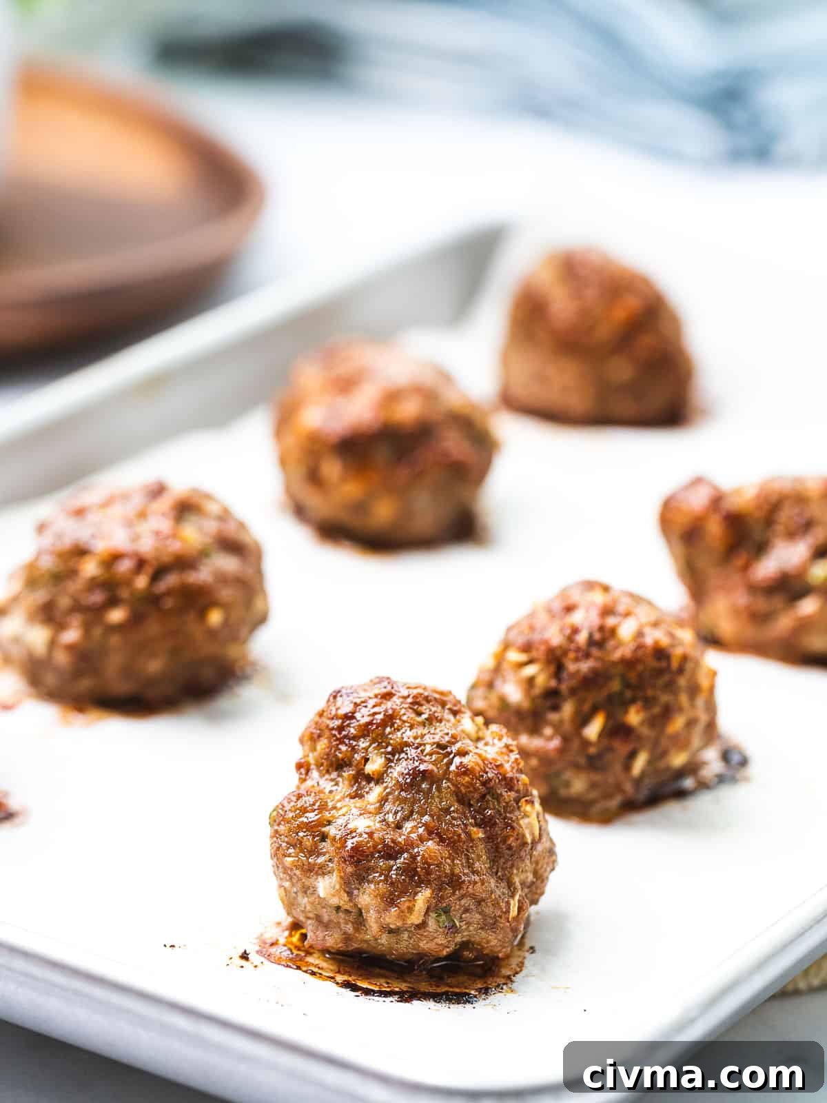 Baked Italian meatballs on a baking tray with a golden brown crust.