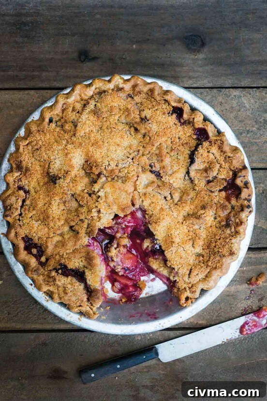German Plum Cake Recipe 3 A baked plum crumble pie with a serving cut from it and a knife on the table beside it.