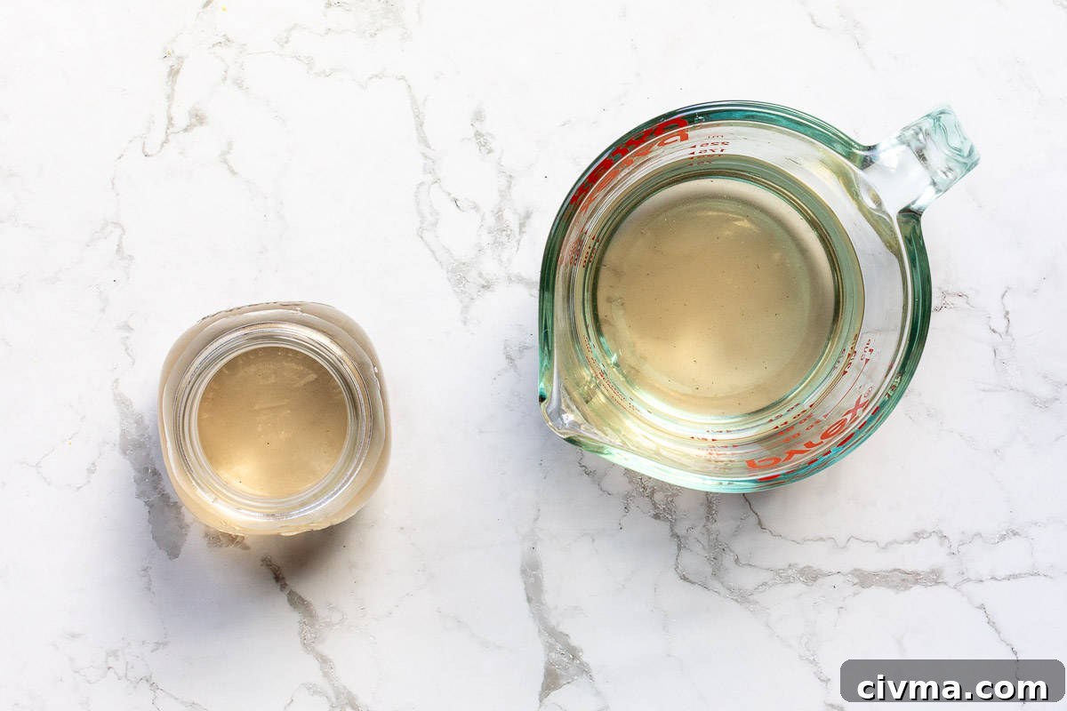 strained syrup in measuring cup next to jar filled with lavender syrup.