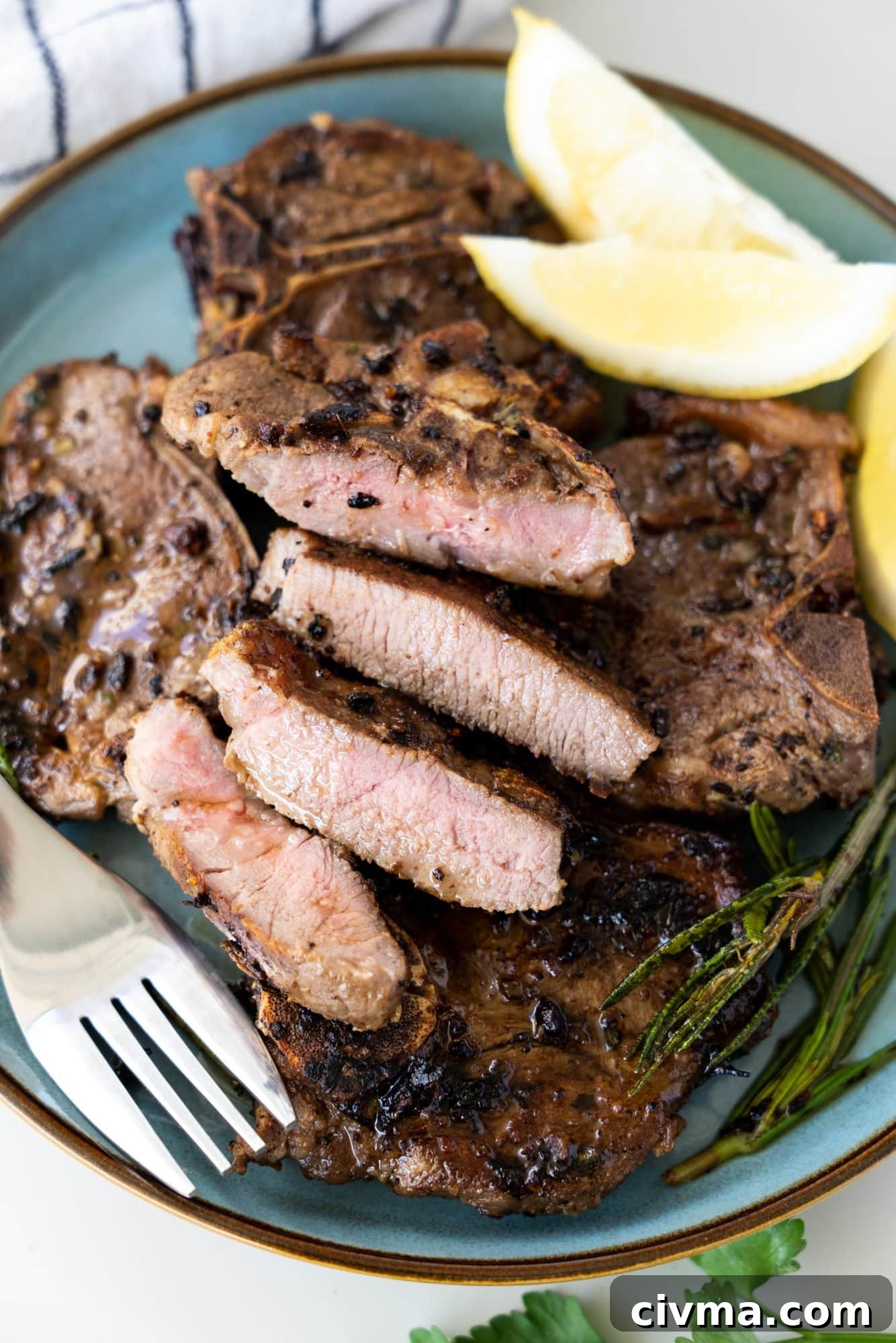 Stack of pan seared lamb chops on a blue plate. One cut to show a pink inside and crusty seared outside.