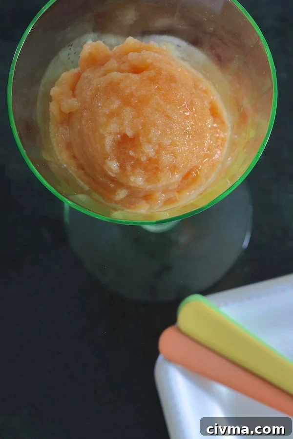A scoop of peach sorbet in a pale green stemmed glass