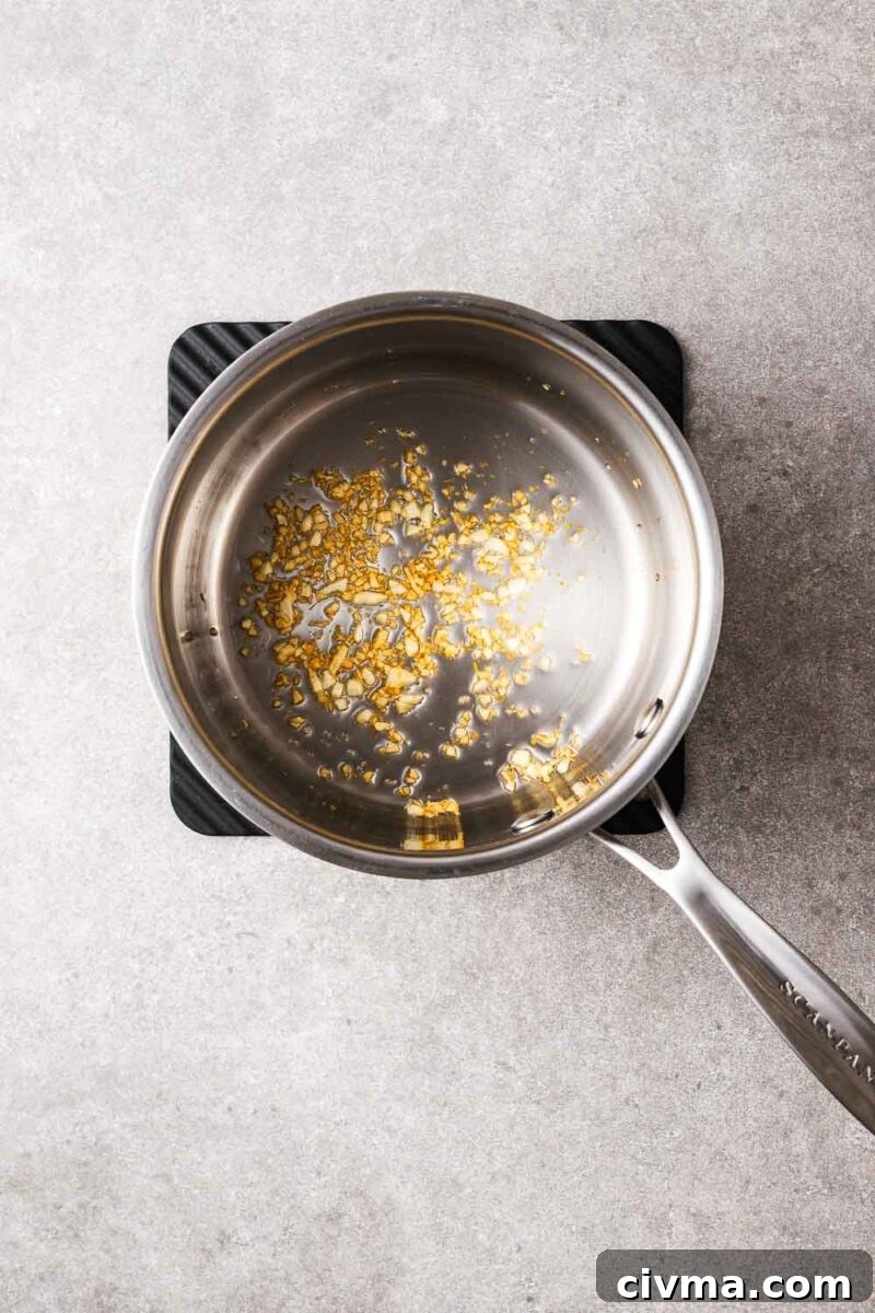 Minced garlic cooked in a saucepan until golden and fragrant.
