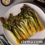 A platter of roasted bok choy lightly browned and garnished with sesame seeds.
