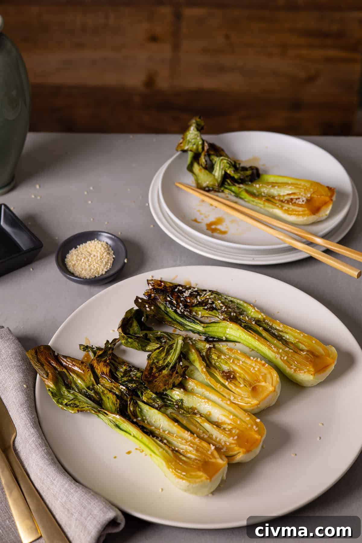Roasted Bok Choy Recipe with Garlic and Sesame 10 A platter of roasted bok choy and a small serving in the background with chop sticks.