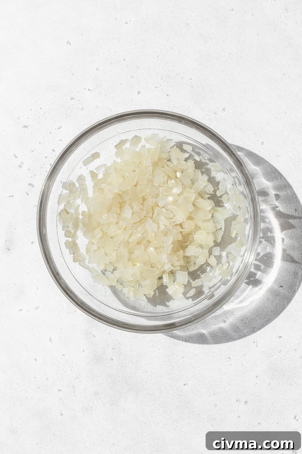 Microwaved minced onion in a glass bowl.