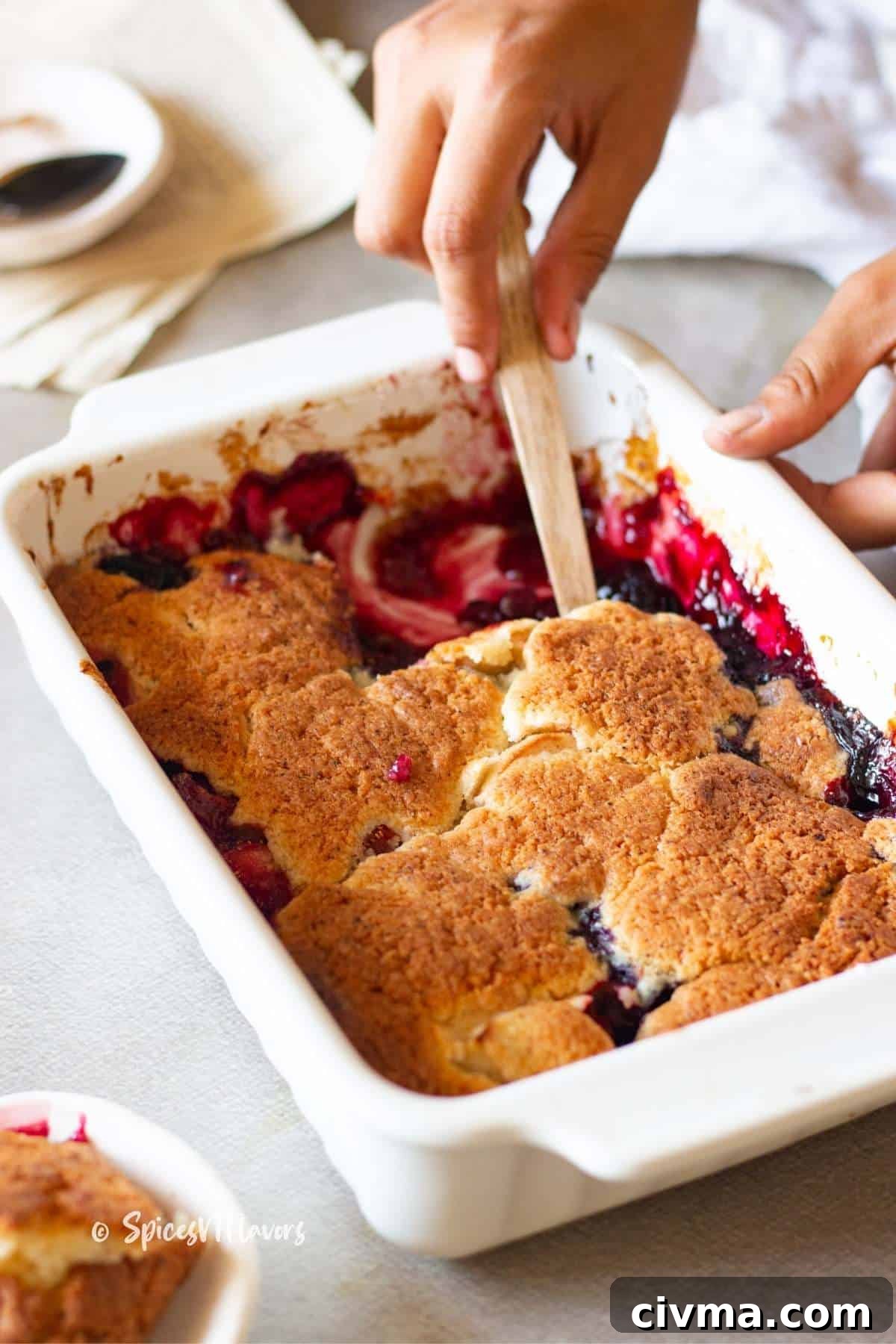 scooping out warm fruit cobbler with a wooden spoon ready to be served