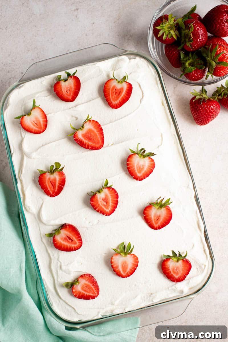 a whole strawberry tres leches cake on a counter for serving.