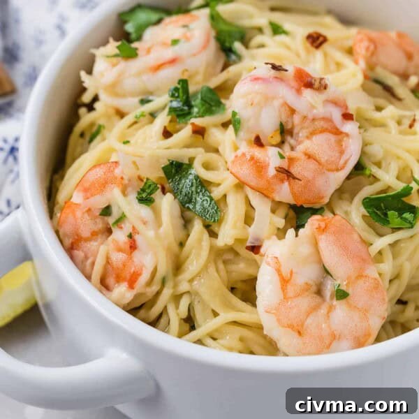Shrimp and pasta in a white bowl, garnished with fresh parsley.