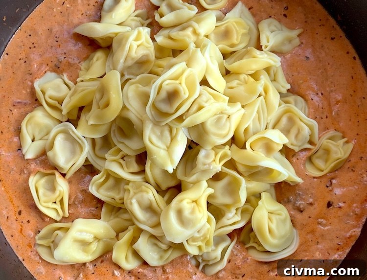 Tortellini mixed with creamy meat sauce in a baking dish.