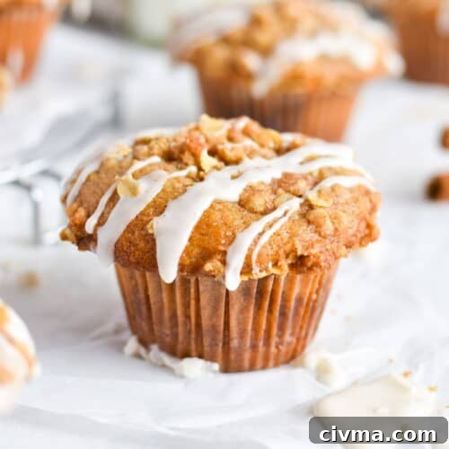 whole muffin with icing dripping off top on white parchment paper.