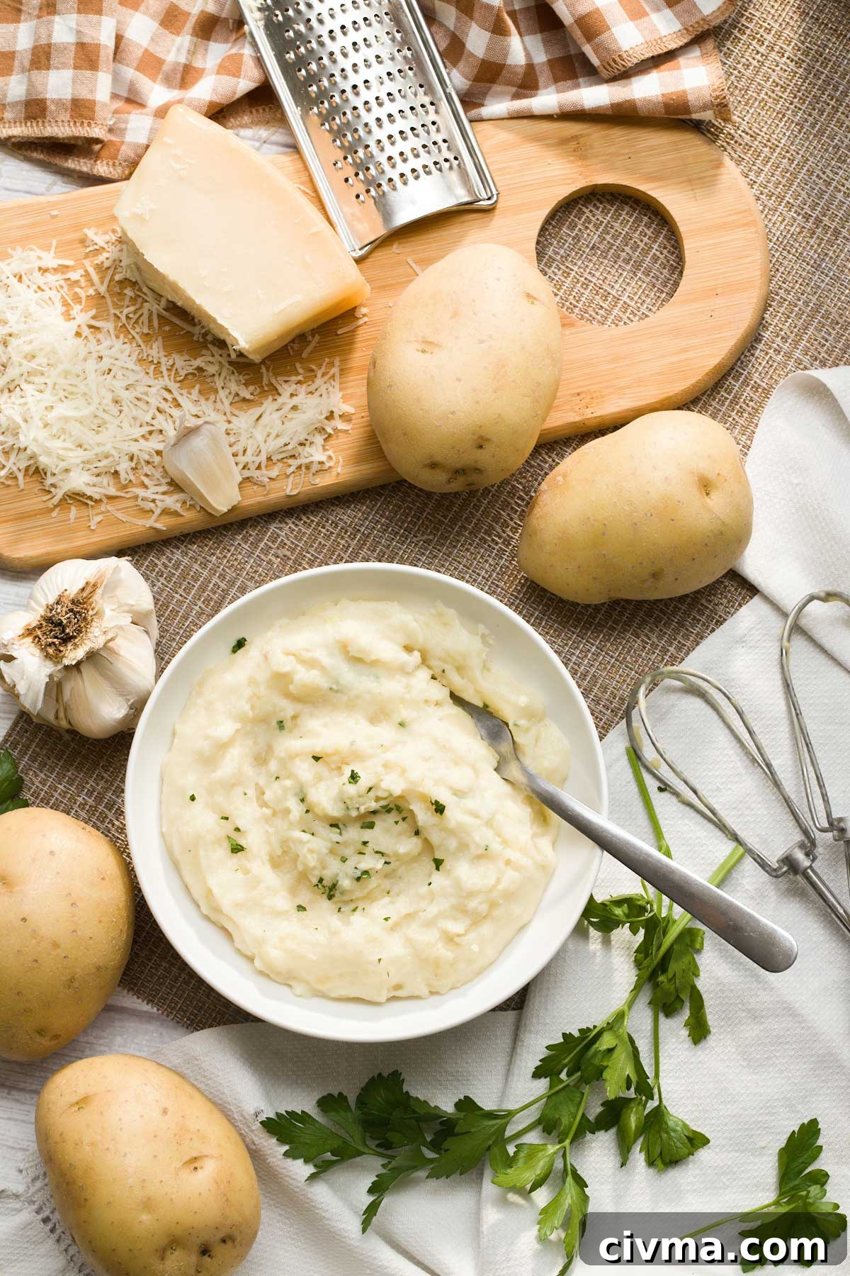 Creamy Garlic Cottage Cheese Mashed Potatoes 4 Top view of a white bowl with creamy garlic mashed potatoes surrounded by potatoes, mushrooms, and shredded cheese.