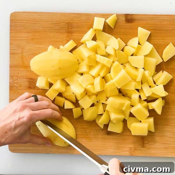 Creamy Garlic Cottage Cheese Mashed Potatoes 5 Dicing the gold potatoes on a cutting board with a knife.