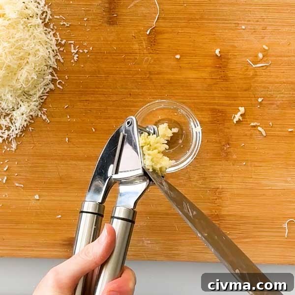 Creamy Garlic Cottage Cheese Mashed Potatoes 9 Mincing garlic in a garlic press and scraping it into a bowl.