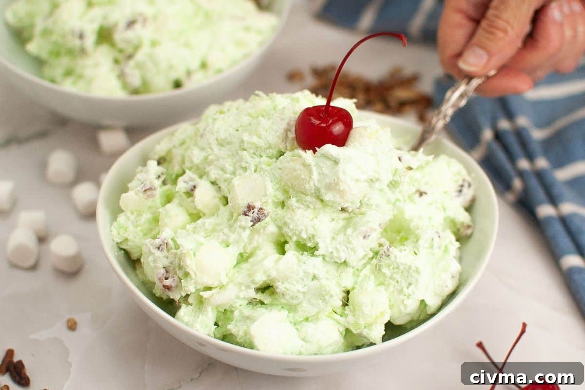 A bowl of Watergate salad topped with a cherry.