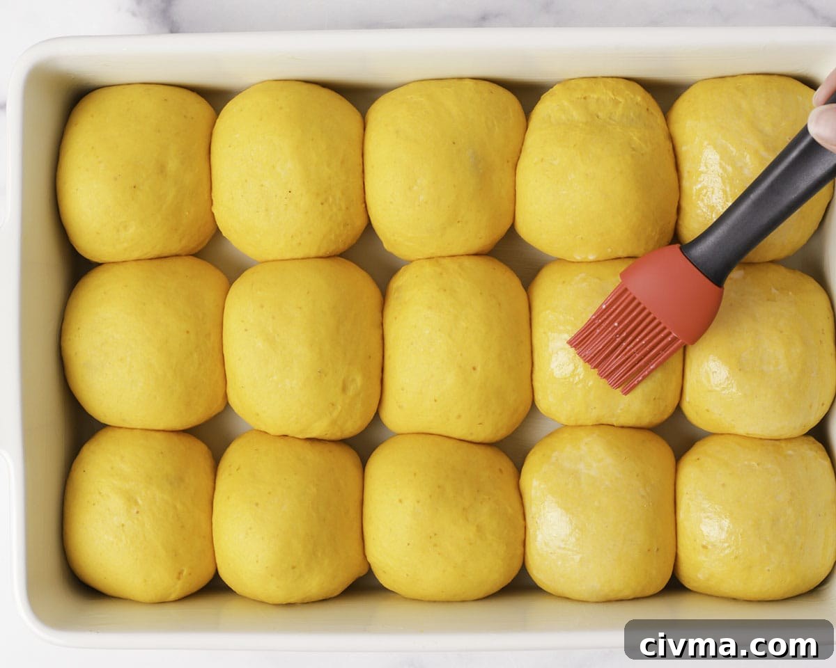 Soft Pumpkin Dinner Rolls Recipe 19 Brushing pumpkin dinner rolls with milk before baking.