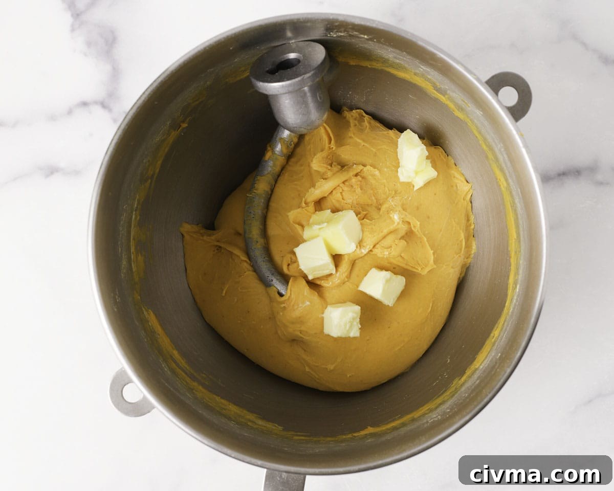 Soft Pumpkin Dinner Rolls Recipe 10 Butter being added to pumpkin roll dough.