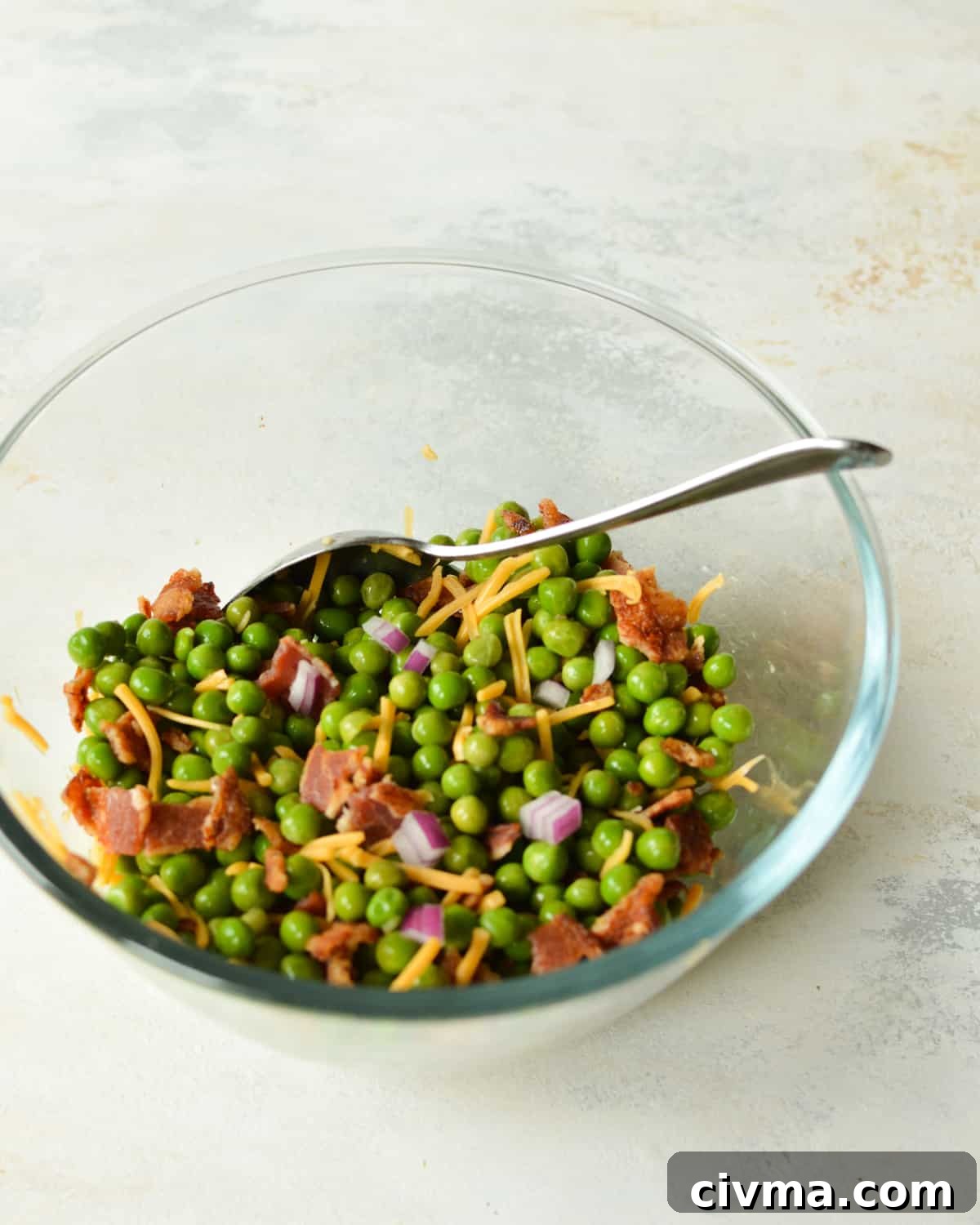a bowl of peas, cheese, red onion, and bacon