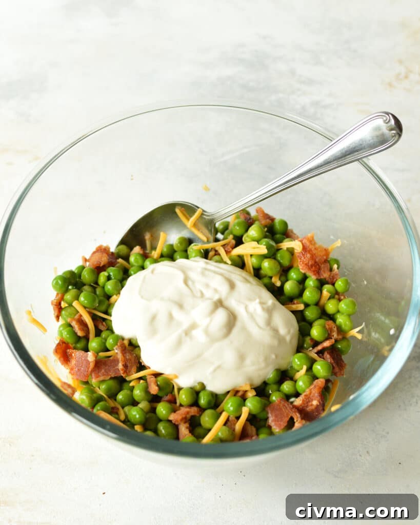 english pea salad being mixed with creamy dressing