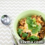 Bowl of turkey chili with hominy topped with cheese and cilantro