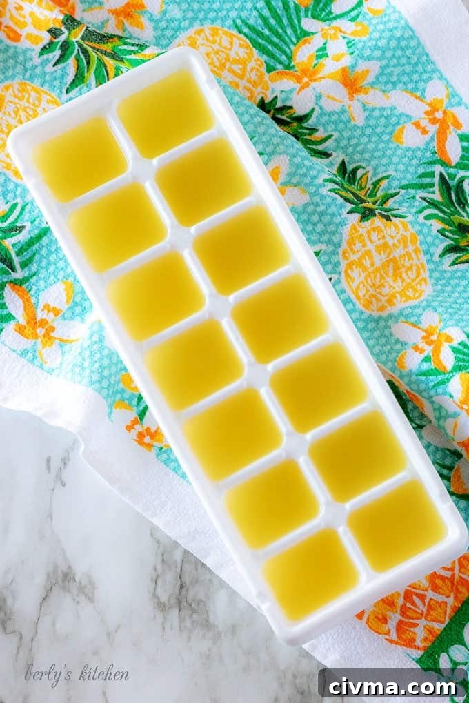 The tropical cocktail mixture poured into a white ice cube tray for freezing.