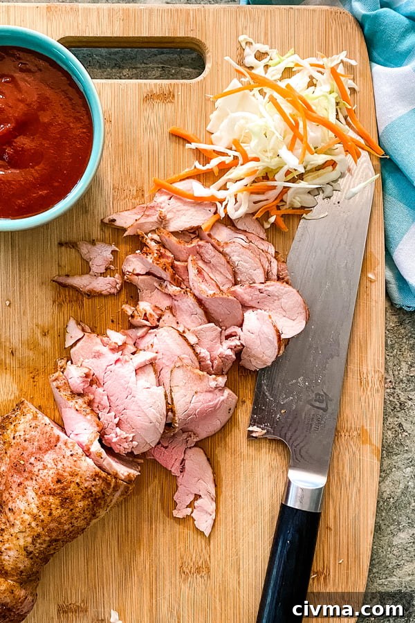 Sliced pork tenderloin and homemade barbecue sauce for sliders on a cutting board.