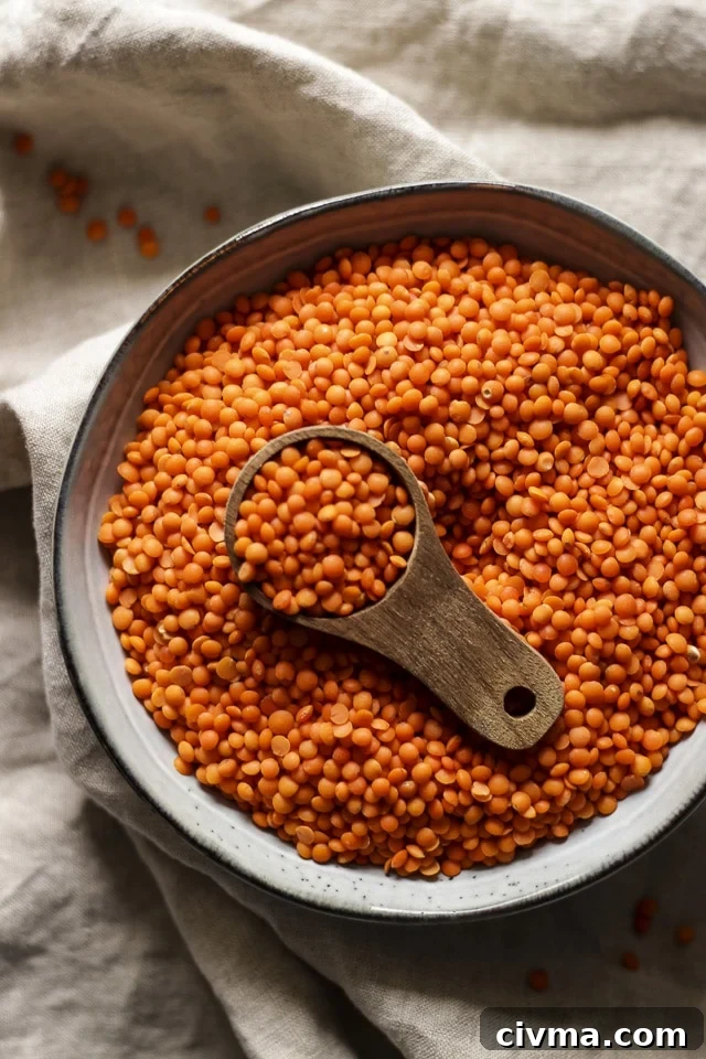 Raw Red Lentils in a Bowl with a Wooden Spoon