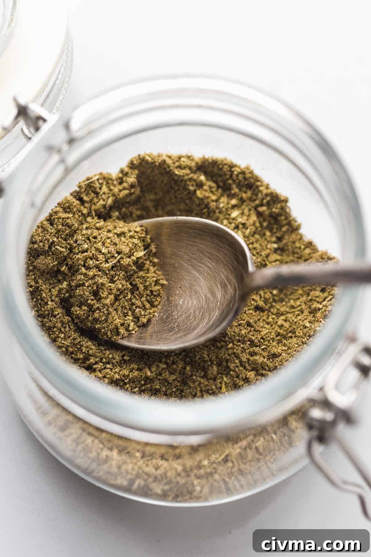 Homemade Poultry Seasoning in a jar with a spoon