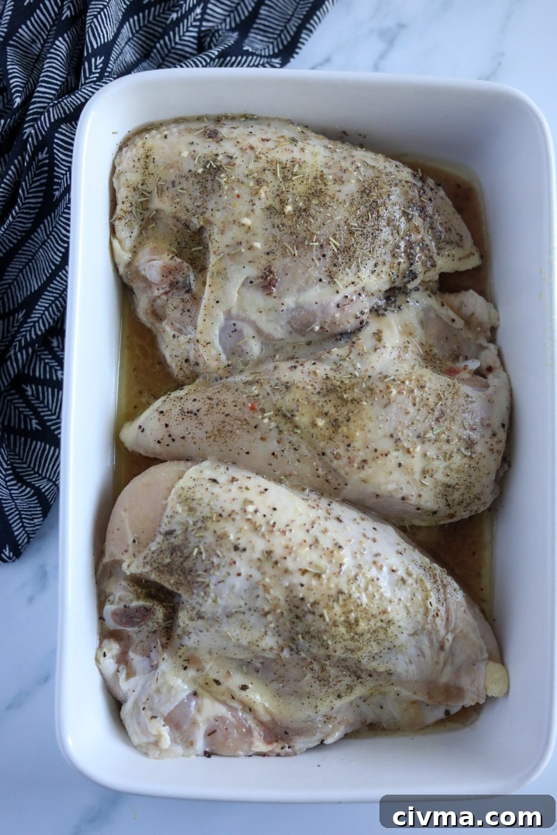 raw, seasoned chicken breasts in a glass white dish.