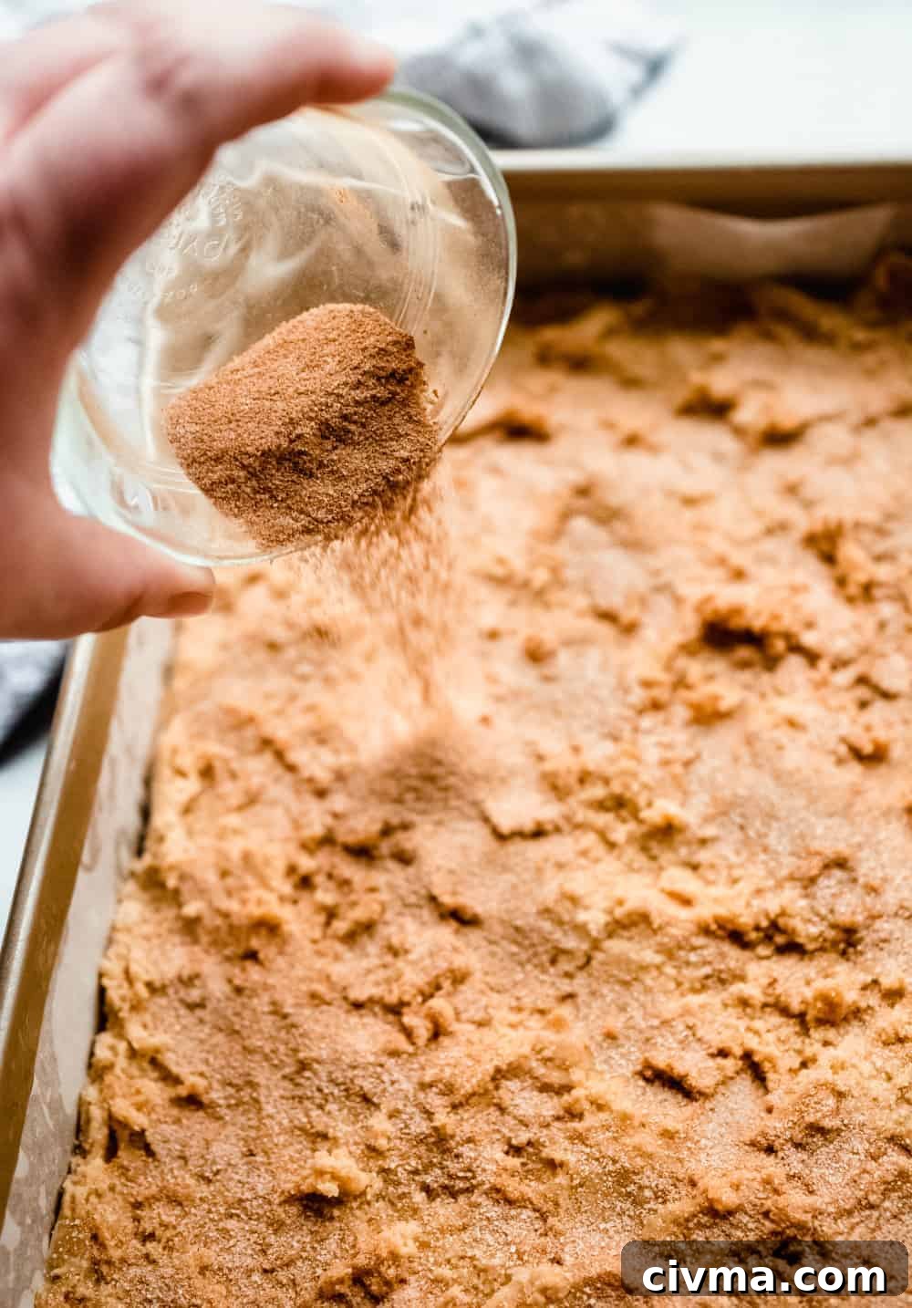 Hand sprinkling cinnamon-sugar over the dough for snickerdoodle blondies