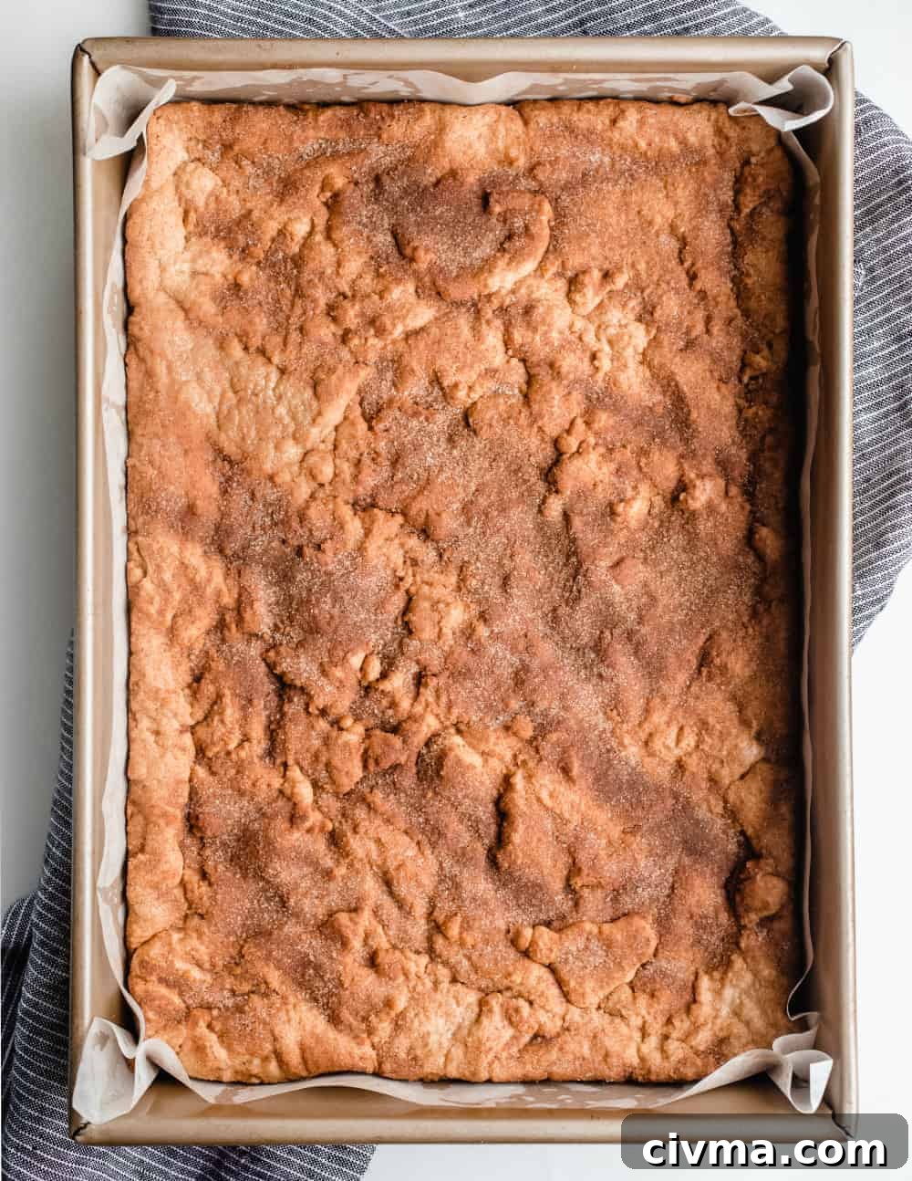 Freshly-baked snickerdoodle blondies in a parchment-lined pan, ready to be cut