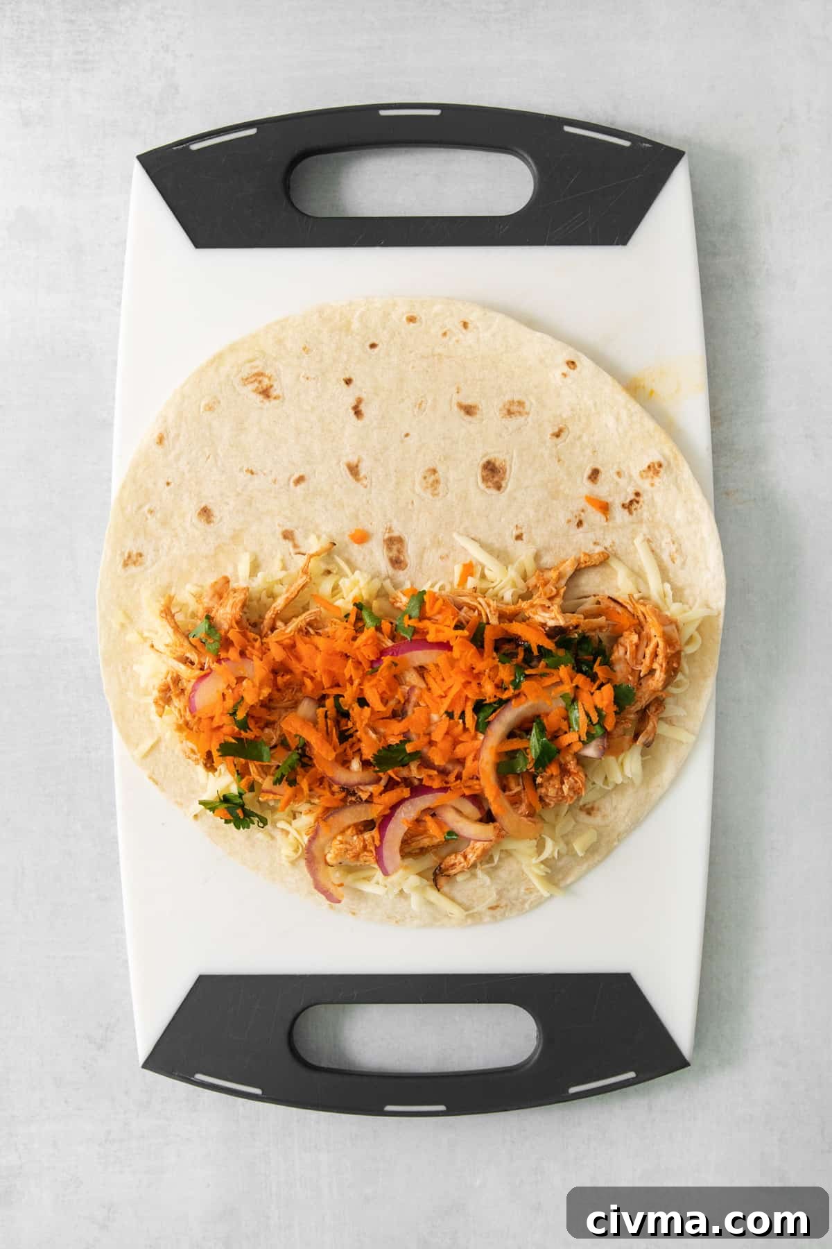 Buffalo Chicken Quesadilla Recipe 3 A taco on a cutting board with carrots and onions.