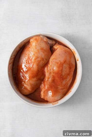 Buffalo Chicken Quesadilla Recipe 8 Two chicken breasts in a bowl on a white surface.