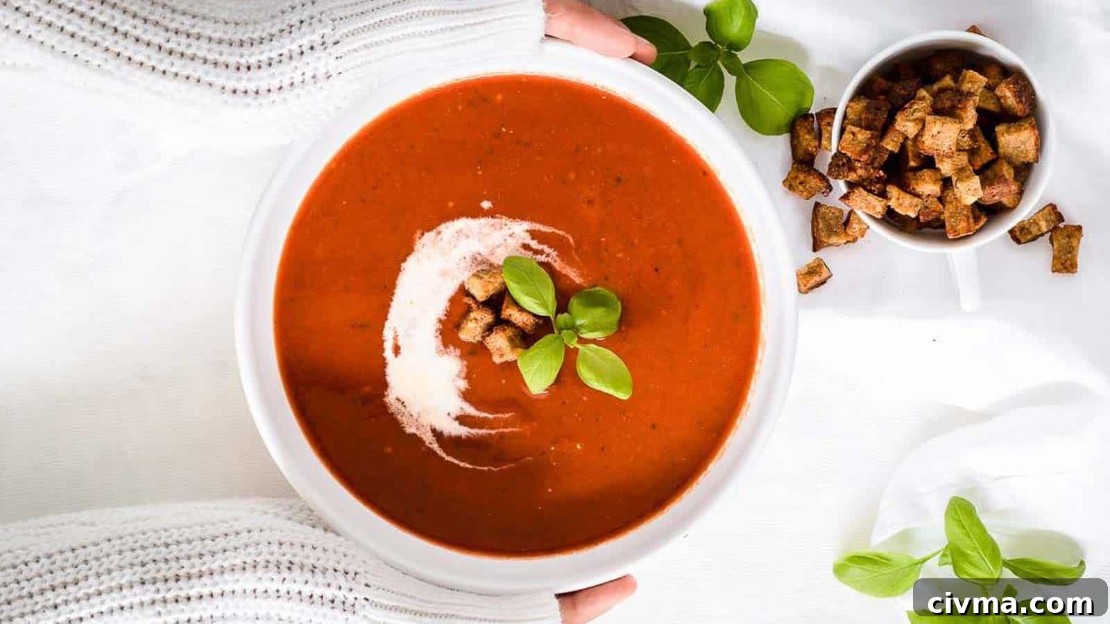 A girl holding a bowl of tomato soup.