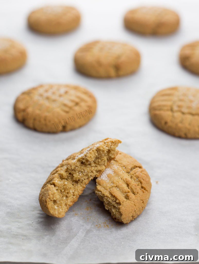 Gluten-Free Chewy Peanut Butter Cookies Recipe 2 Baked gluten free peanut butter cookies on sheet pan with one cookie split in half.