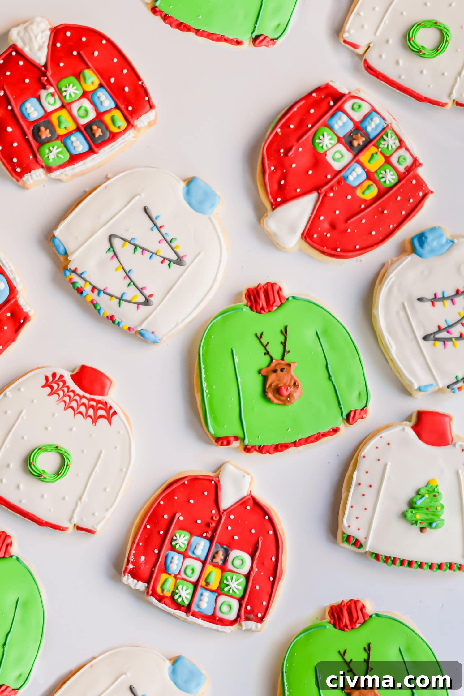 An overhead photo of decorated gluten-free ugly sweater sugar cookies on a white surface.