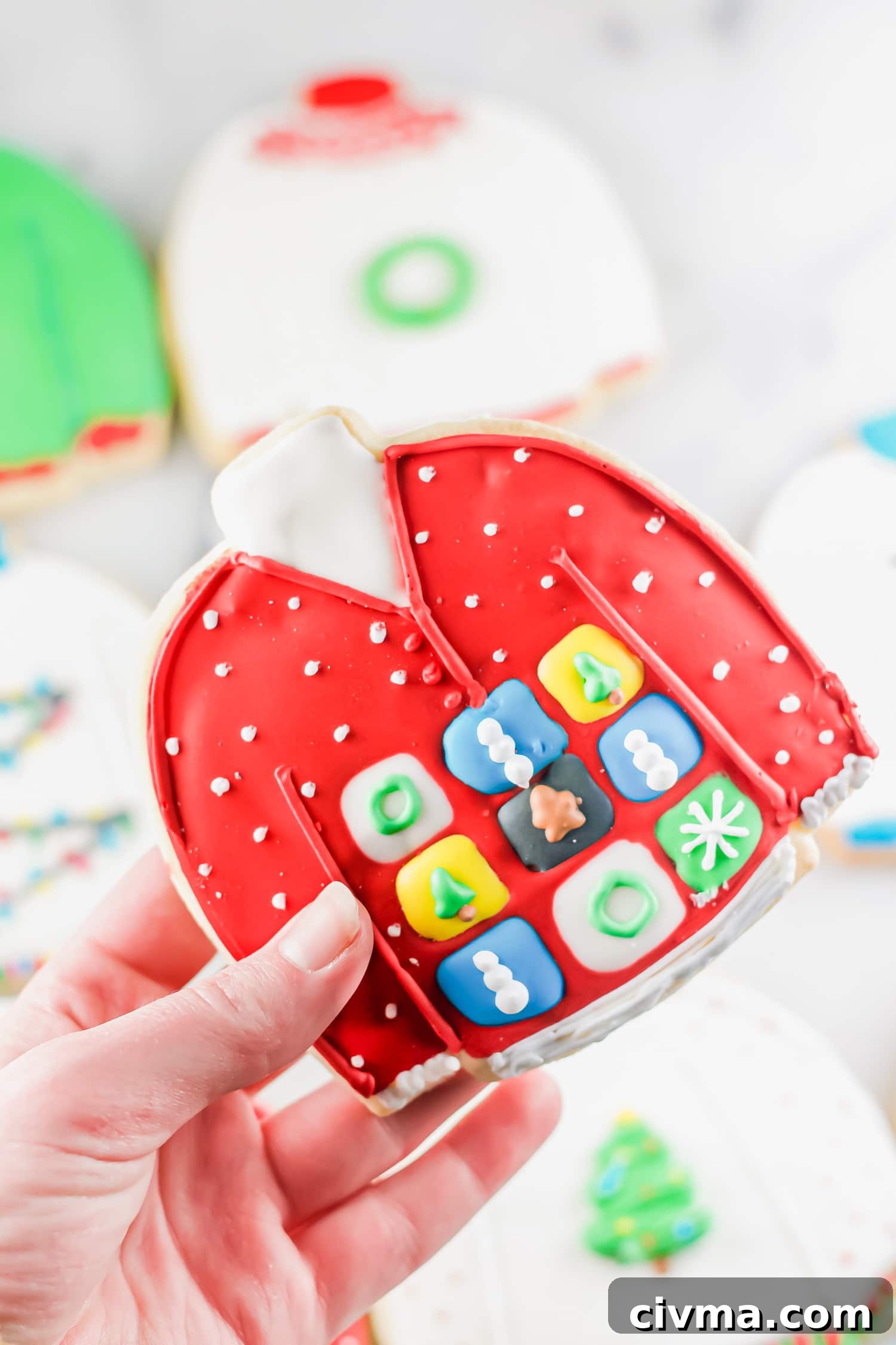 A photo of a hand holding a gluten-free ugly sweater cookie.