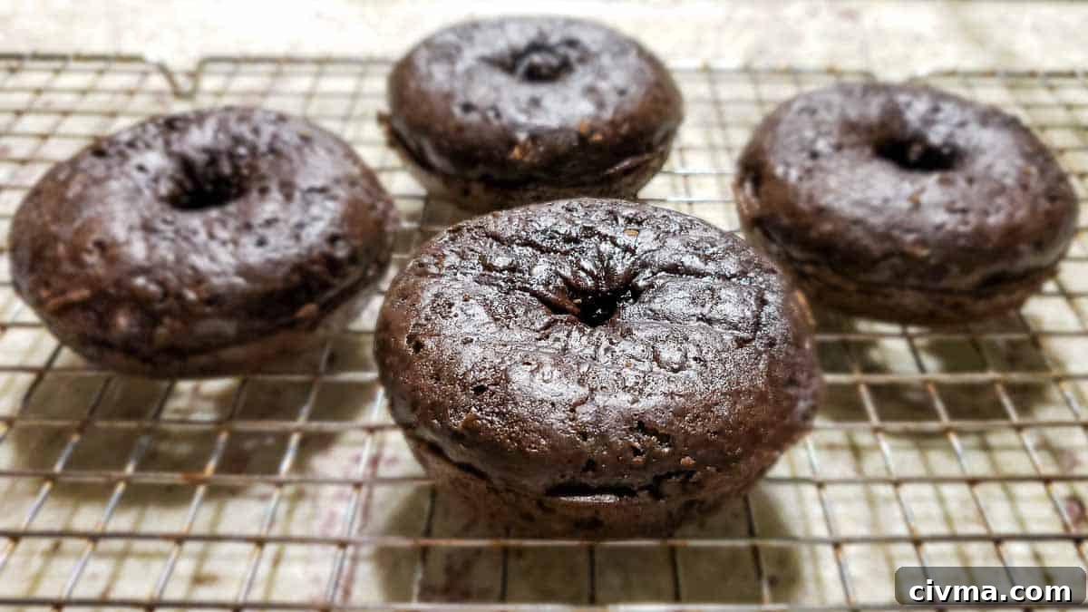 4 baked donuts cooling on a rack.