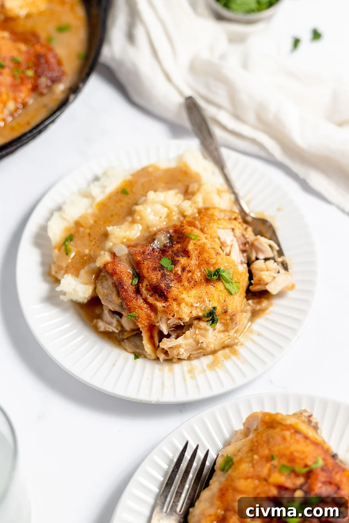 Smothered Chicken Thigh on a plate with mashed potatoes and gravy.