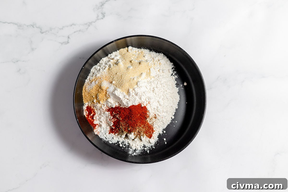 Flour onion powder, garlic powder, paprika, salt, and pepper in a bowl.