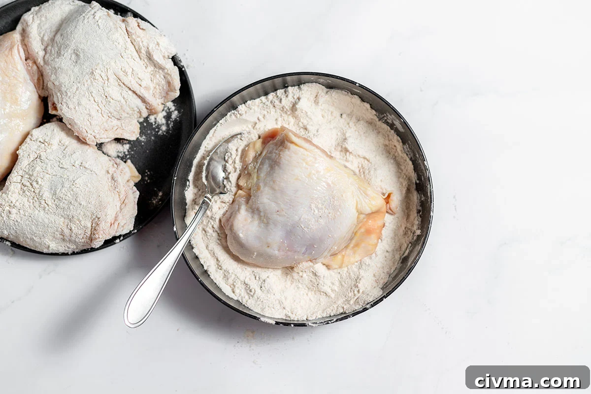 Chicken is coated in flour mixture in a bowl.