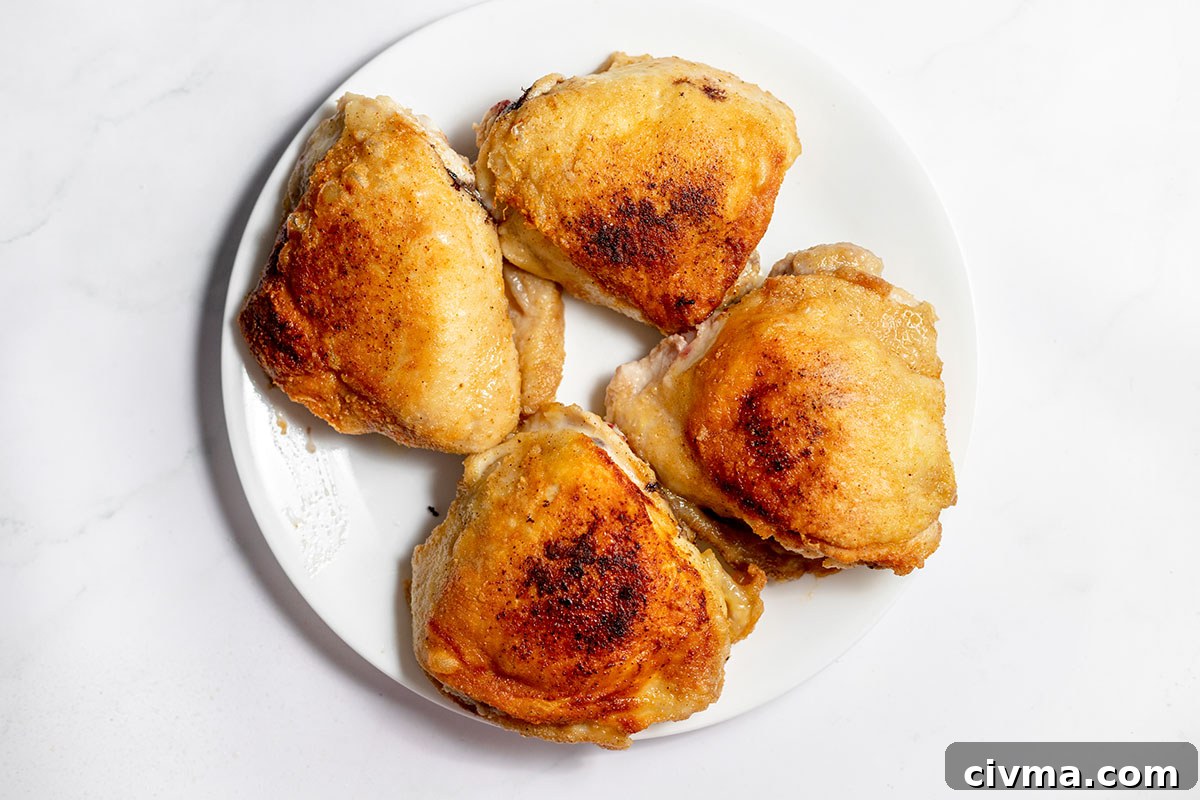 Browned chicken thighs on a plate.