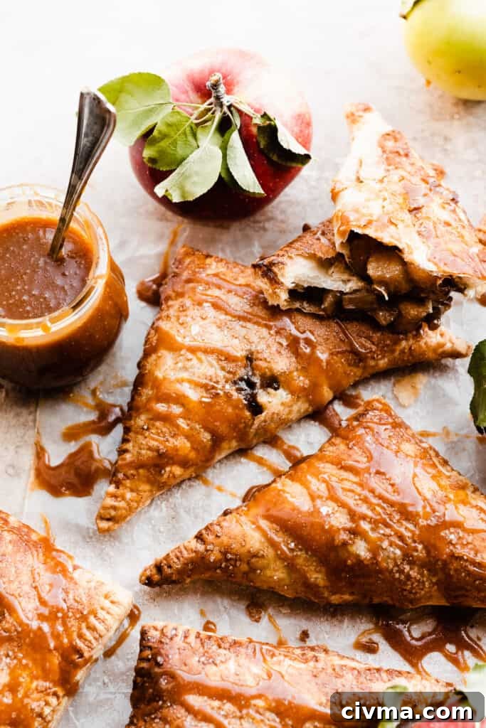 Apple turnovers drizzled with salted caramel sauce, with one broken open near a jar of caramel sauce.