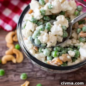 Bowl of cauliflower salad with peas and cashews.