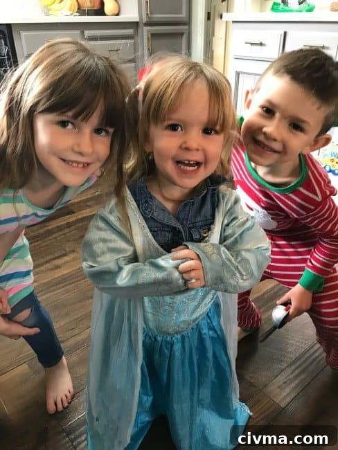 Three children smiling in assorted outfits.