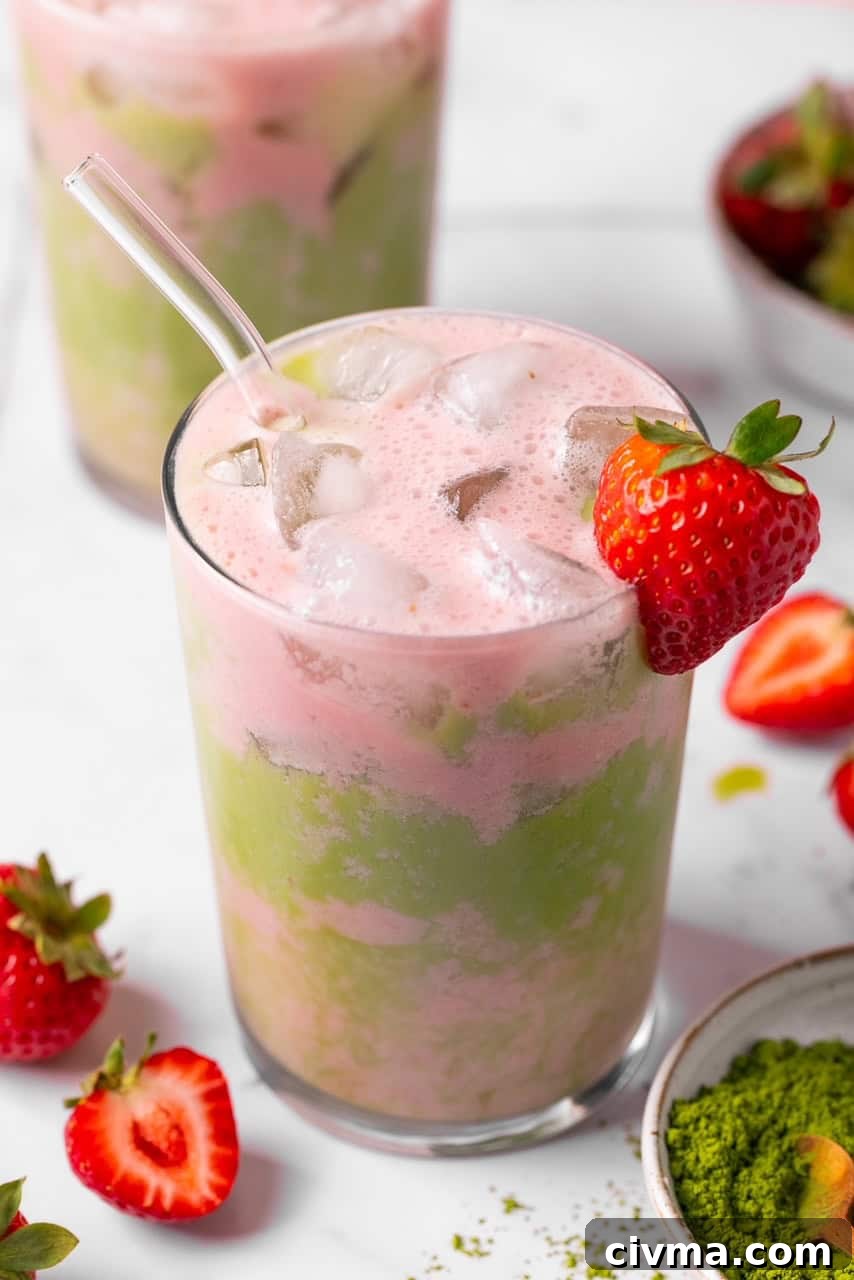 Iced Strawberry Matcha Latte Recipe 2 an iced matcha strawberry tea latte in a glass with a strawberry