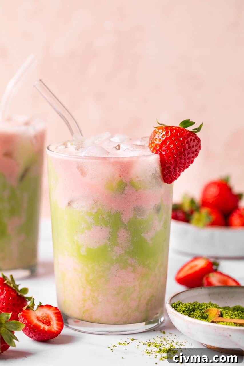 Iced Strawberry Matcha Latte Recipe 6 an up close photo of a matcha strawberry tea latte in a glass with a straw and a strawberry